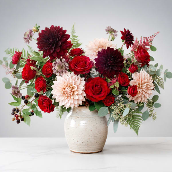 Bouquet of red and blush flowers in a speckled ceramic vase