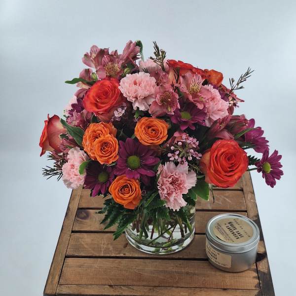Mixed bouquet of roses, carnations, and daisies in a clear glass vase