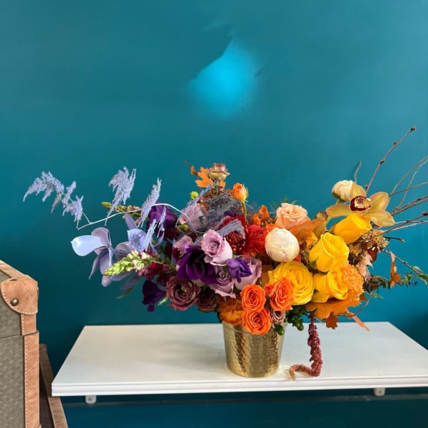 Mixed bouquet of roses and orchids in a gold vase