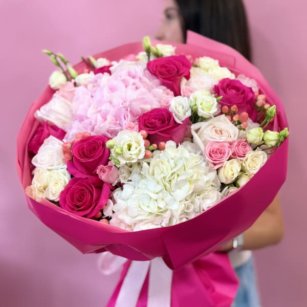 Pink and white bouquet of roses and hydrangeas wrapped in magenta paper