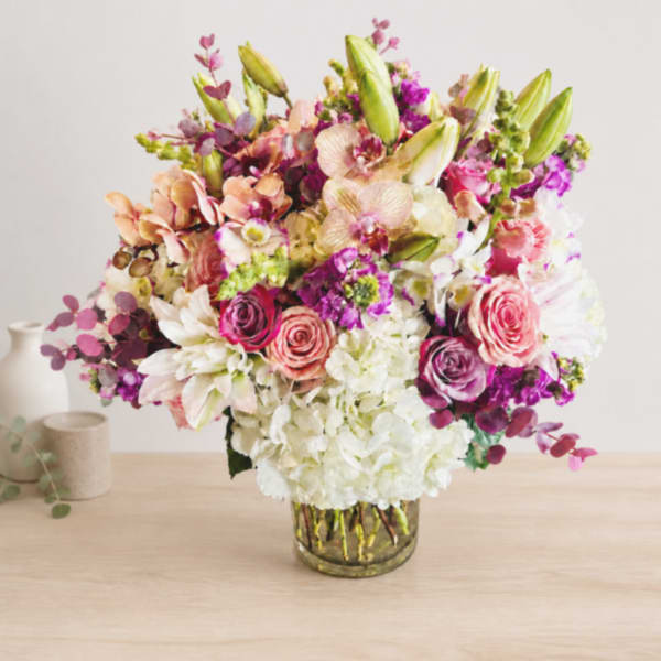 Mixed bouquet of pink, white, and purple flowers in a glass vase