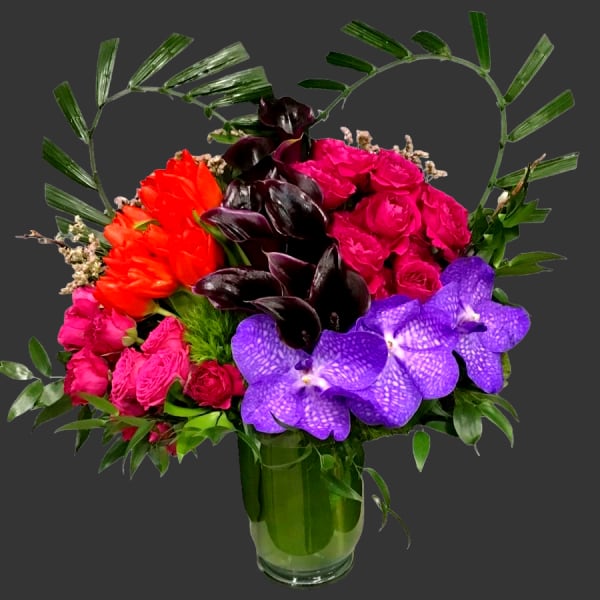 Colorful bouquet with roses, orchids, and tulips in a glass vase