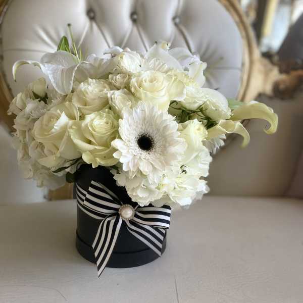 White rose and lily bouquet in a black hat box with striped ribbon