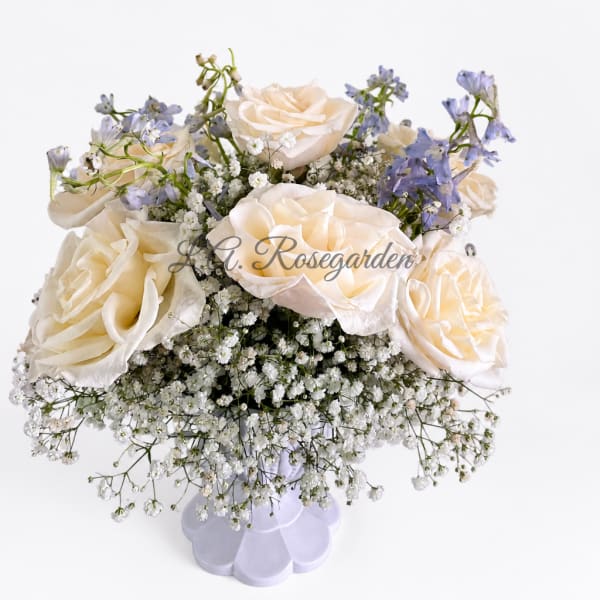 Cream roses with blue flowers in a white vase