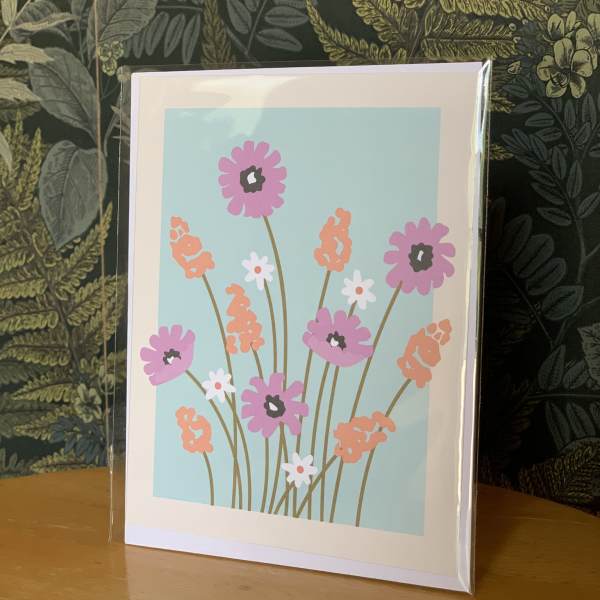 Floral greeting card with pink and orange flowers on a blue background