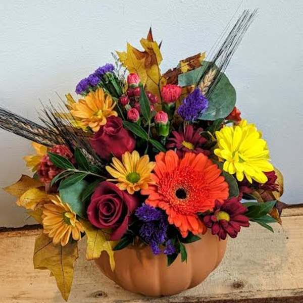 Mixed autumn bouquet in a pumpkin-shaped container with bright flowers