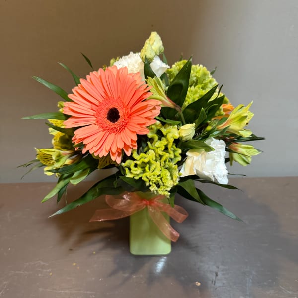 Coral gerbera bouquet with white and green flowers in a green vase