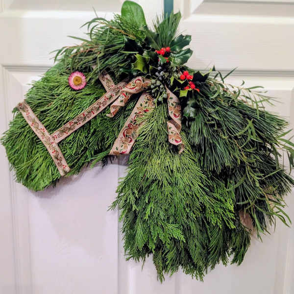 Horse head door swag made of evergreen branches with ribbon and red berries