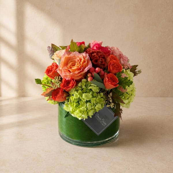 Mixed bouquet of orange and pink roses in a green glass vase