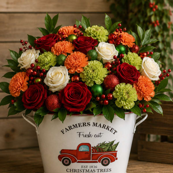 Red, white, orange, and green floral arrangement in a white metal bucket