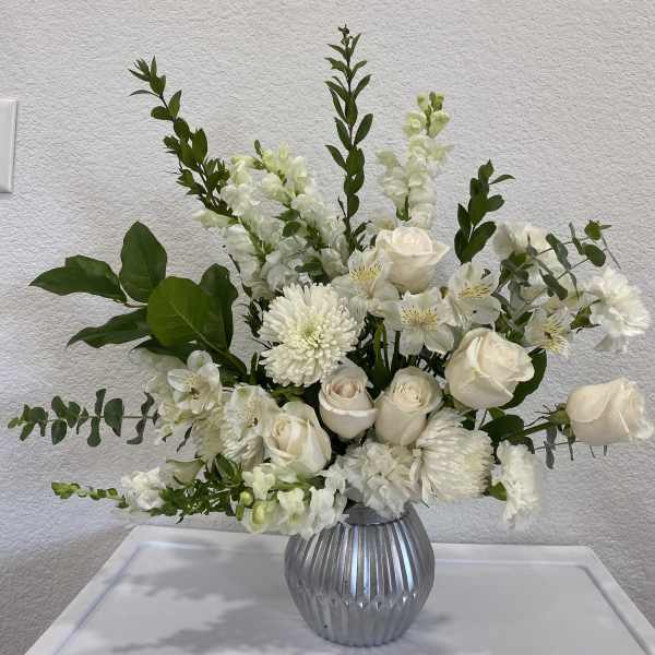 White floral arrangement in a ribbed silver vase