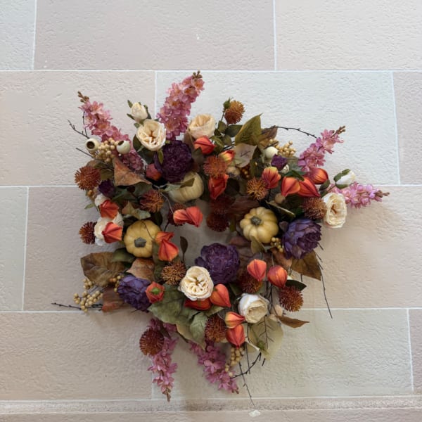 Autumn floral wreath with purple, orange, and cream blooms