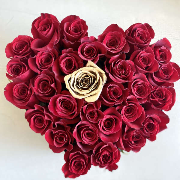 Heart-shaped bouquet of red roses with one cream rose in the center