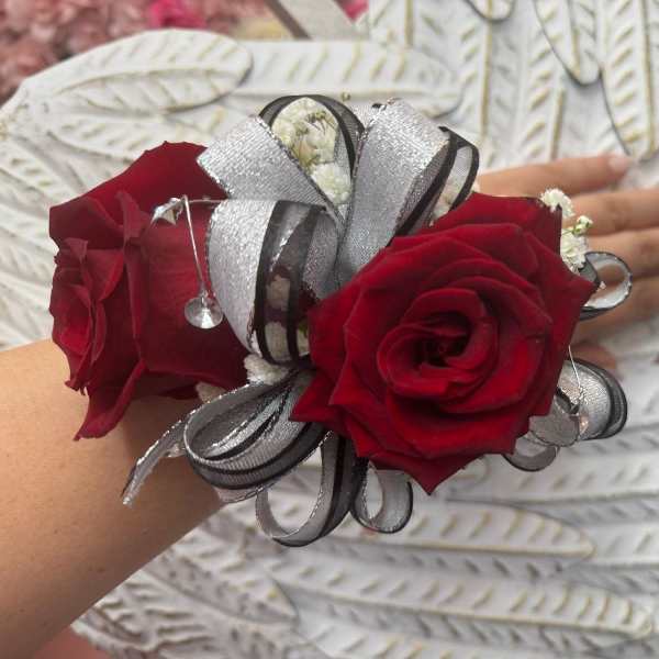 Red rose corsage with silver ribbon on a wrist