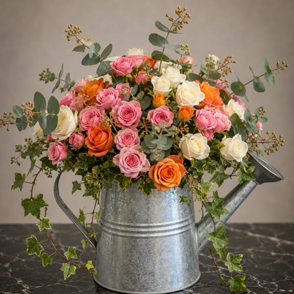 Pink, white, and orange roses in a metal watering can
