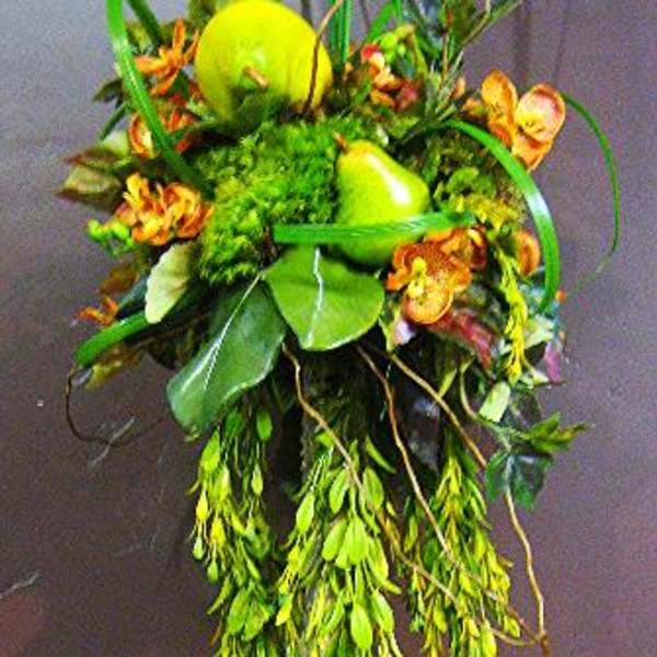 Tall floral topiary with green fruit accents in a white planter