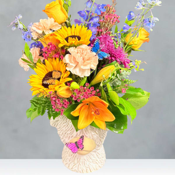 Colorful mixed bouquet in a cream vase with butterfly accents