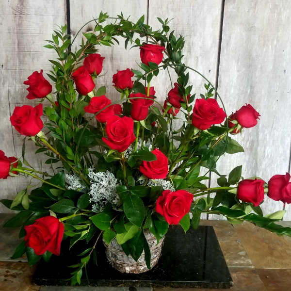 Red roses arranged in a basket with arched greenery