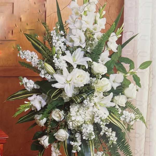 Tall white floral standing spray with lilies and roses on a metal easel