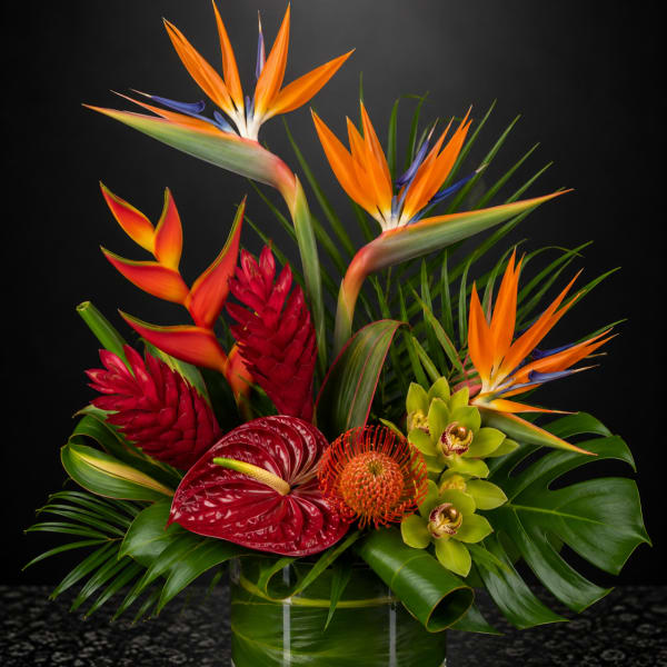 Tropical arrangement with bird of paradise, anthurium, and orchids in a glass vase