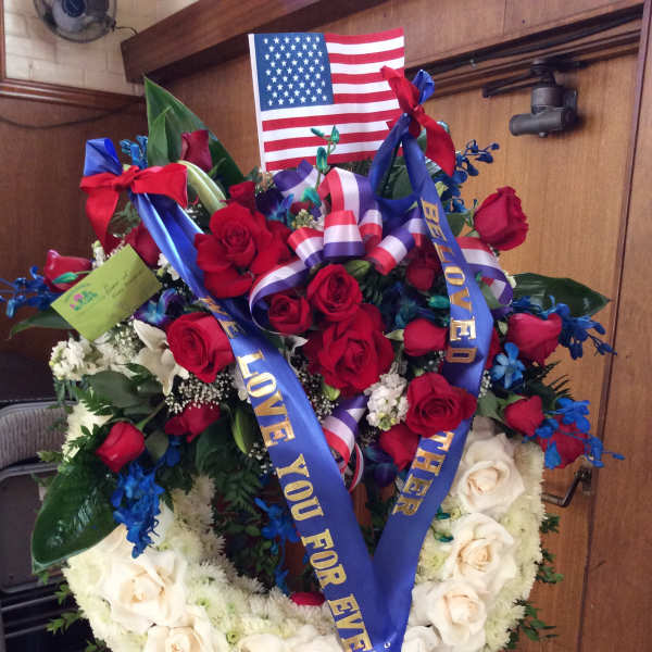 Heart-shaped floral wreath with red and white roses and patriotic ribbons
