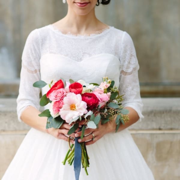 Bride holding a pink and red bouquet with greenery