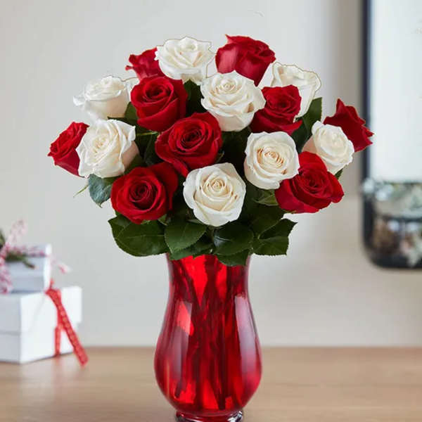 Red and white roses arranged in a red glass vase