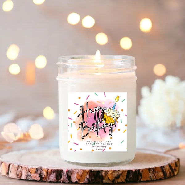 Birthday cake scented candle in a glass jar with a lit wick