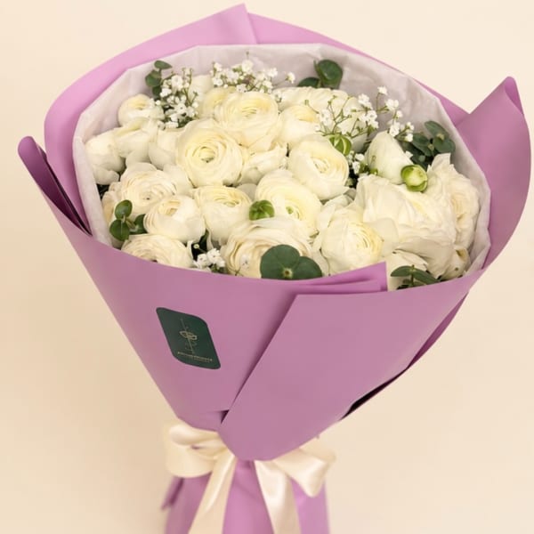 Bouquet of white ranunculus wrapped in lavender paper with a ribbon