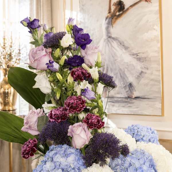 Tall floral arrangement with blue hydrangeas, purple lisianthus, and pink carnations