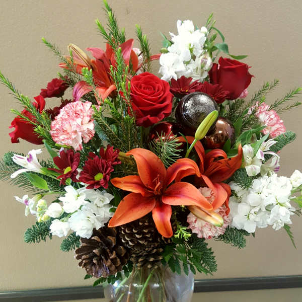 Red and white floral arrangement in a glass vase with lilies and roses