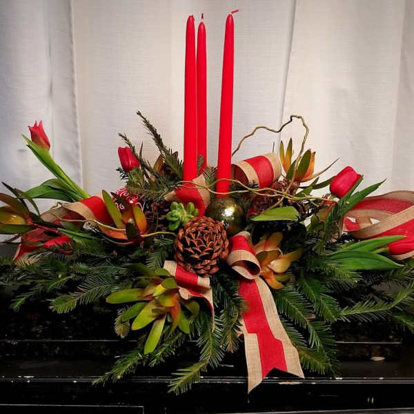 Holiday centerpiece with red candles, pinecones, and red ribbon