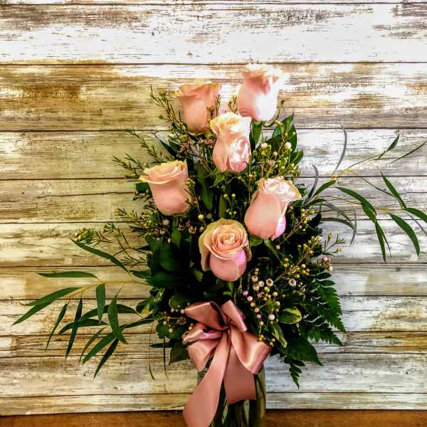 Pink roses arranged in a glass vase with a satin ribbon