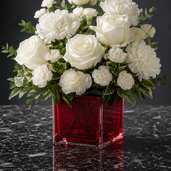 White roses and carnations in a red glass vase