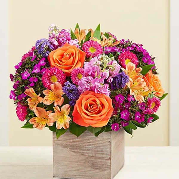 Mixed bouquet with orange roses and pink-purple flowers in a wooden box