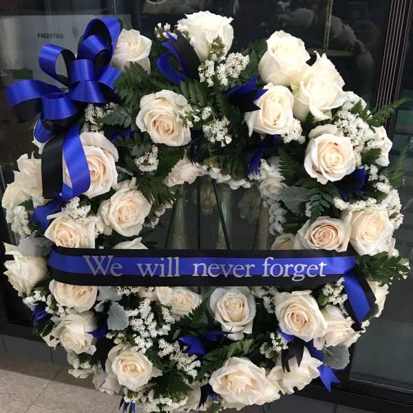 White rose funeral wreath with blue ribbon on an easel