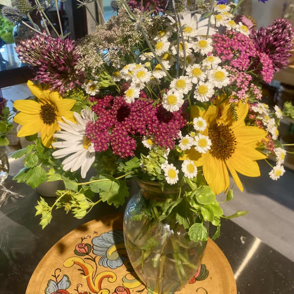 Mixed bouquet with sunflowers, white daisies, and purple allium in a glass vase