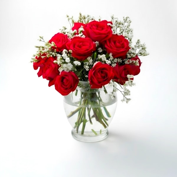 Red roses arranged in a clear glass vase with white filler flowers