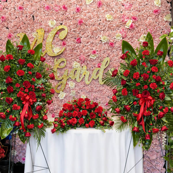 Large floral display with red roses and carnations against a pink flower wall