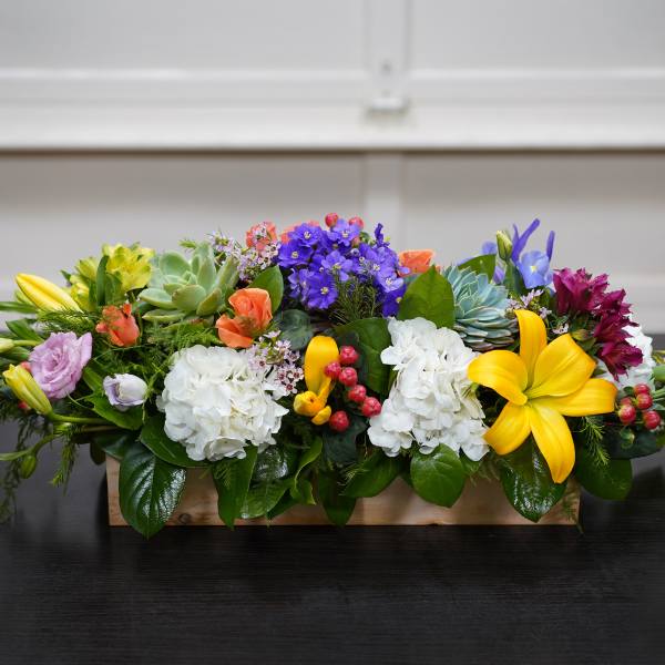 Colorful mixed flower arrangement in a low wooden box