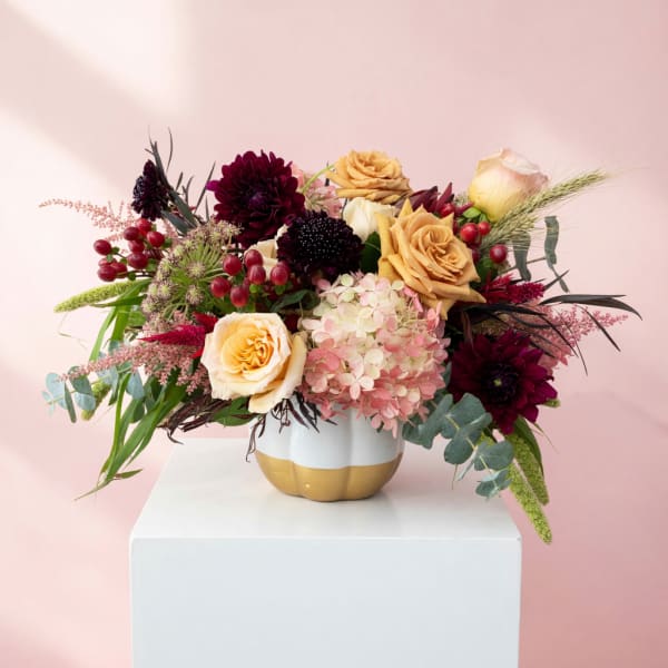 Mixed bouquet of roses and hydrangeas in a gold-and-white vase