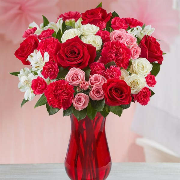 Bouquet of red, pink, and white roses in a red glass vase