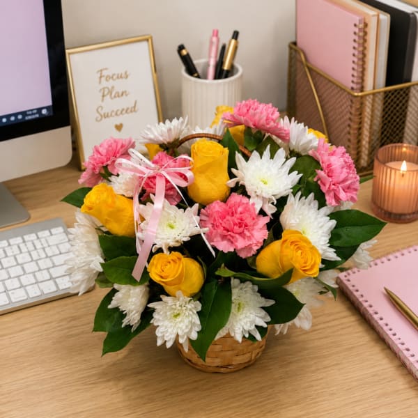 Basket arrangement of yellow roses, pink carnations, and white daisies