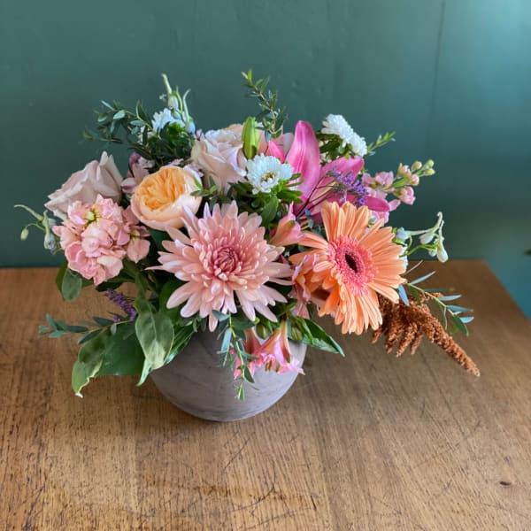 Mixed pink and peach flowers arranged in a gray vase