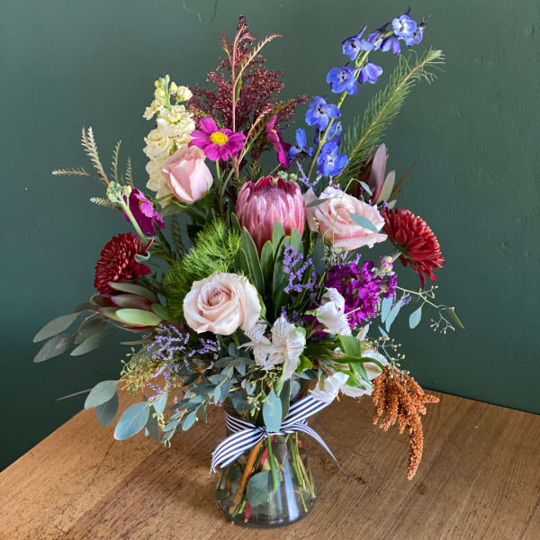 Mixed bouquet in a glass vase with pink, purple, white, and red blooms