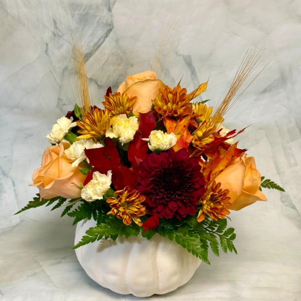 Autumn bouquet of roses and chrysanthemums in a white pumpkin vase