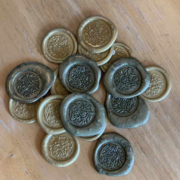 Stack of floral-patterned wax seals in gold and dark gray