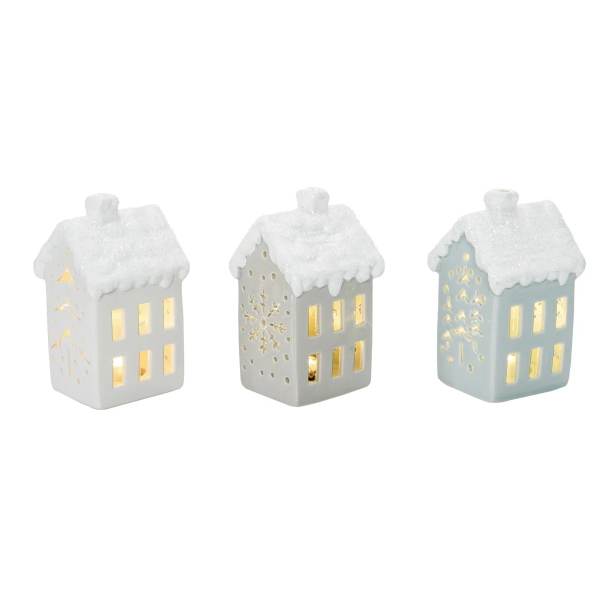 Three small ceramic house lanterns with glowing windows and snowy roofs