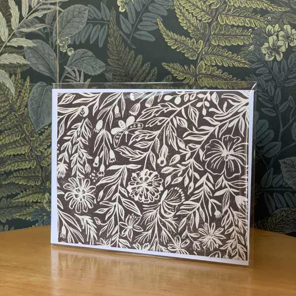 Floral-patterned greeting card in a clear sleeve on a wooden table