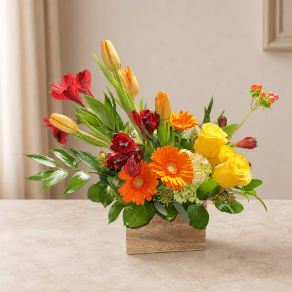 Mixed bouquet with yellow roses, orange gerberas, and red alstroemeria in a wooden box